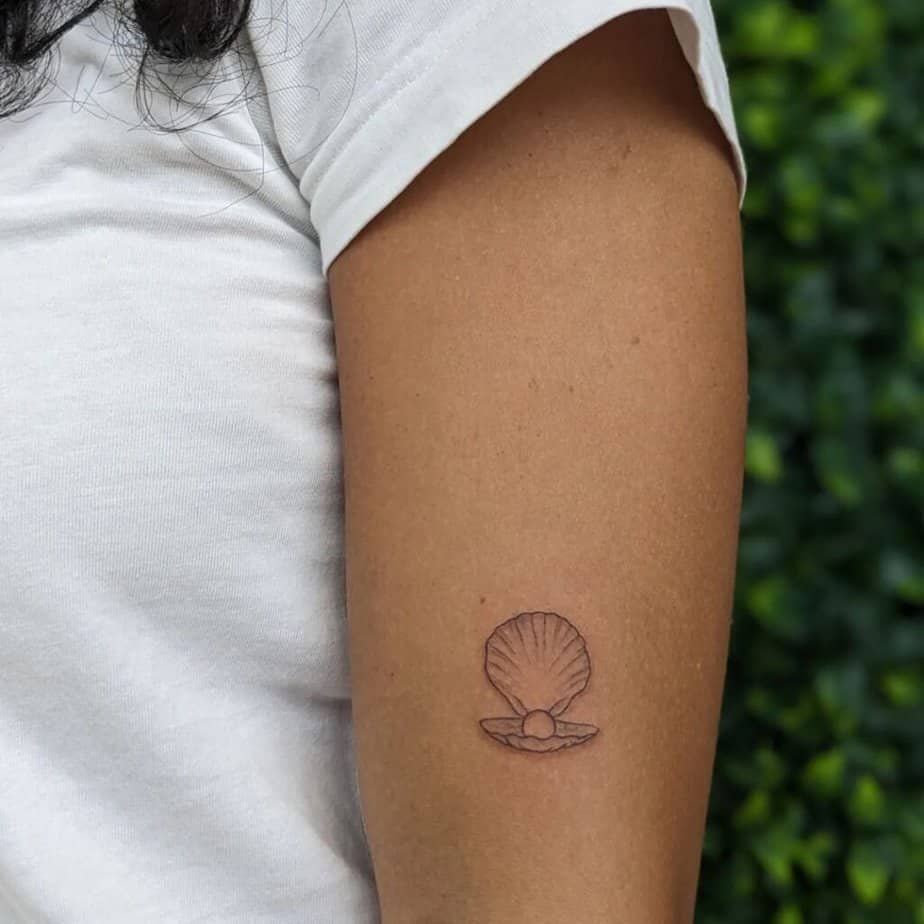 21. A delicate and dainty seashell pearl tattoo 