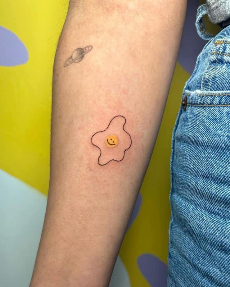 3. A tattoo of a smiley face egg on the forearm