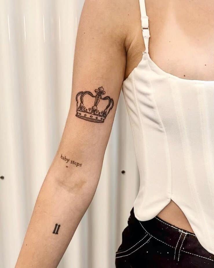 1. A fine-line crown tattoo on the bicep