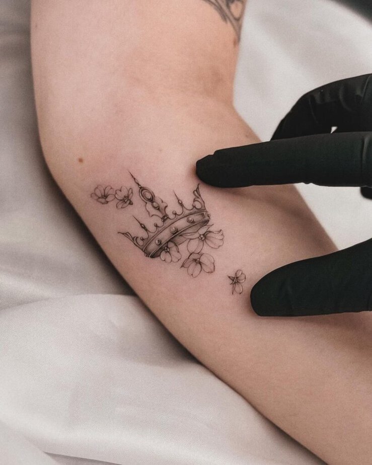 21. A fine-line crown tattoo with flowers