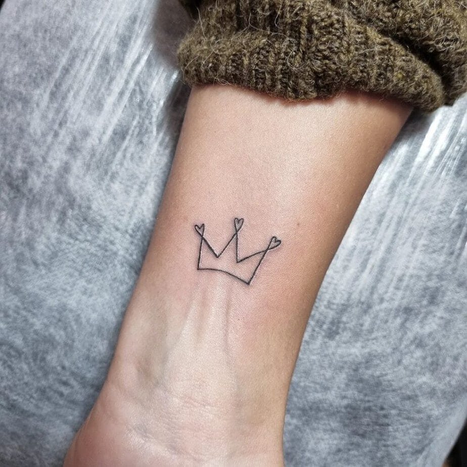 23. A linework crown tattoo on the wrist