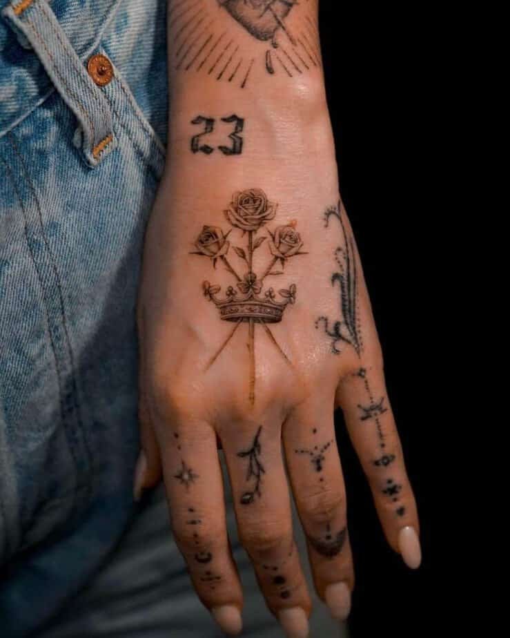 5. A tattoo of a crown with three roses on the hand