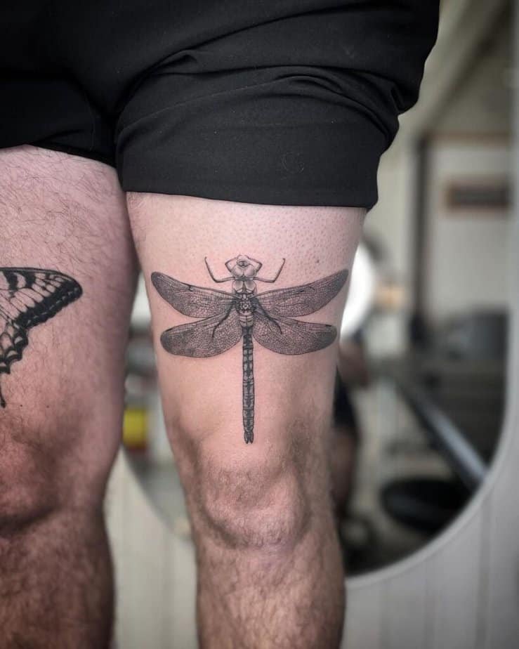 7. A big and bold thigh tattoo of a dragonfly