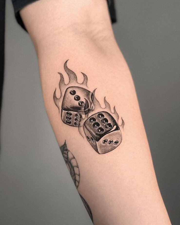 5. A forearm tattoo of dice with flames 