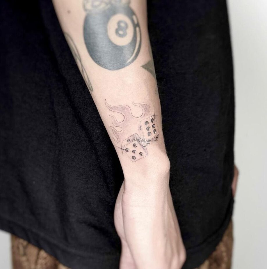 6. A wrist tattoo of dice with flames