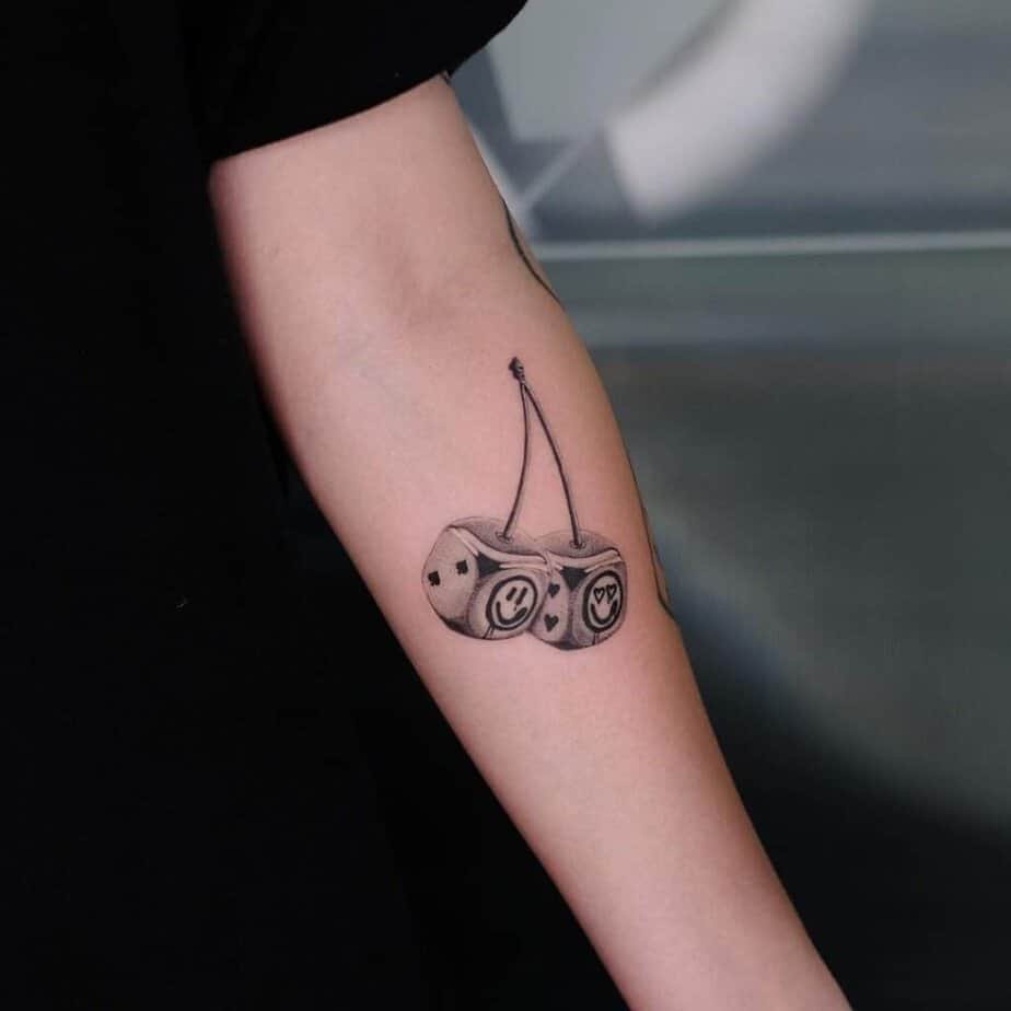 9. Chrome cherry dice tattoo on the forearm