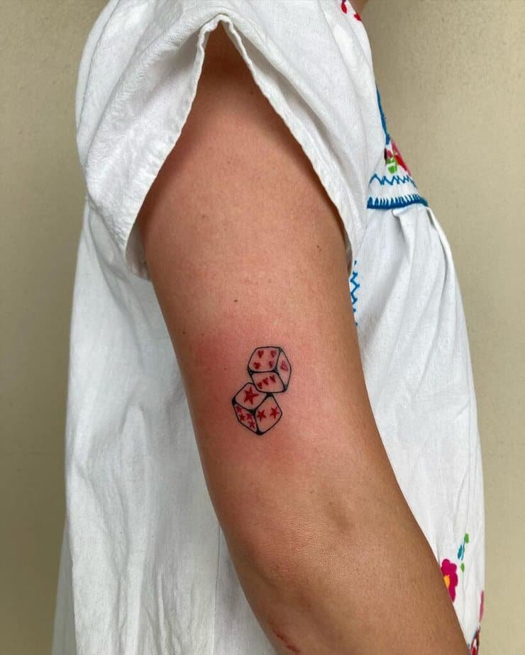 15. Black and red dice tattoo on the upper arm